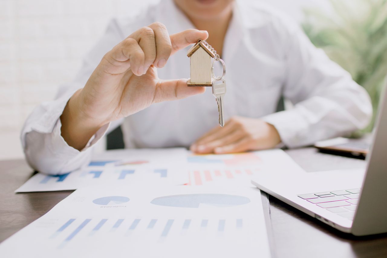 our-story Real estate professional presenting a house model with keys, symbolizing property investment and ownership.